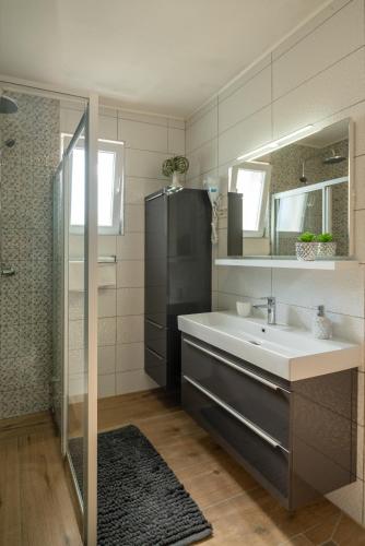 a bathroom with a sink and a shower and a mirror at Apartmani "MARKO" Dugovača in Drage