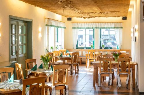 Un restaurante con mesas y sillas de madera y ventanas. en Parkpension Spreewald, en Burg