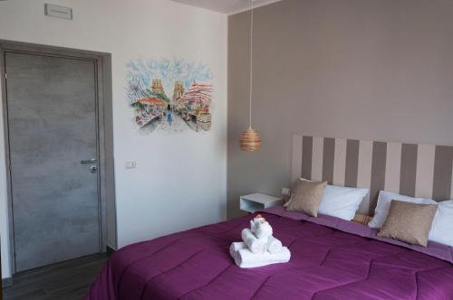 a purple bed with a stuffed animal sitting on it at La Piccola Formica Charme Rooms in Palermo