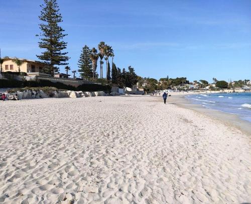 a person walking on a sandy beach near the ocean at Villa Sogno sulla Spiaggia in Fontane Bianche