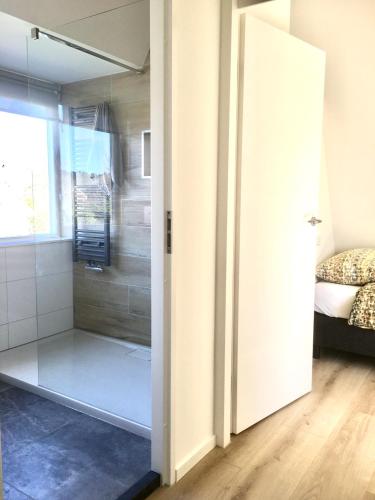a bathroom with a shower and a glass door at Bendalong Noordwijk in Noordwijk