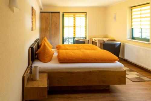 a bedroom with a bed with an orange blanket on it at Pension Kräutermühlenhof Burg in Burg