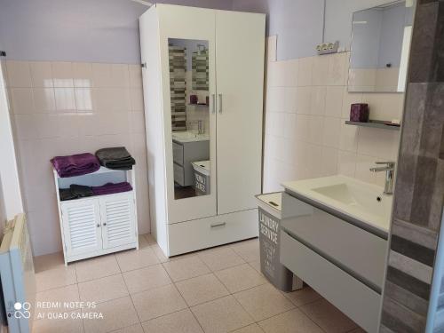 a white bathroom with a sink and a mirror at La Bedosse in Alès