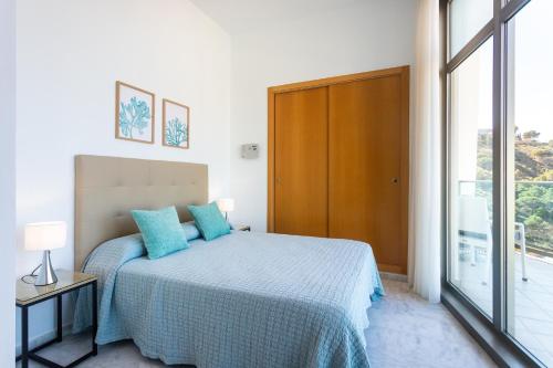 una camera da letto con un letto con cuscini blu e una finestra di Gran terraza privada con vistas espectaculares - Torre Lúgano a Benidorm