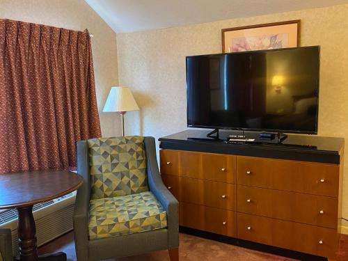 a hotel room with a tv and a chair and a table at Economy Lodge 682 Main St Sturbridge in Sturbridge