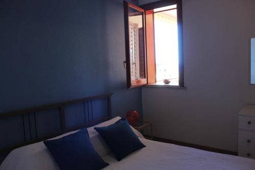a bedroom with a bed with blue walls and a window at CasaLella in Letojanni