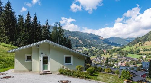 a small house on a hill with mountains in the background at Ferienhäuser Tröster in Bad Kleinkirchheim