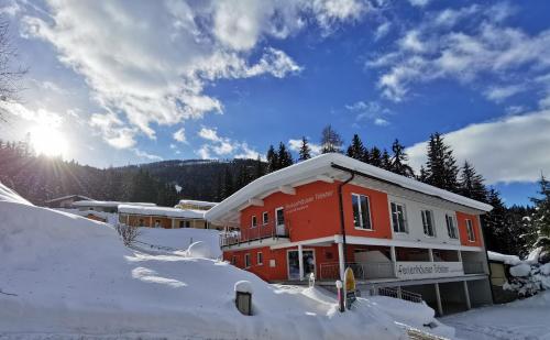 a red building with snow on the ground at Ferienhäuser Tröster in Bad Kleinkirchheim
