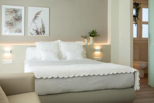 a bedroom with a large bed with white sheets and pillows at Hotel Rural Tierras del Cid in Quintanadueñas