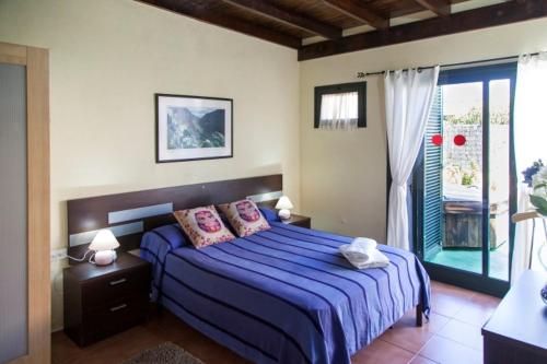 a bedroom with a blue bed and a window at Cuyagua in Corralejo