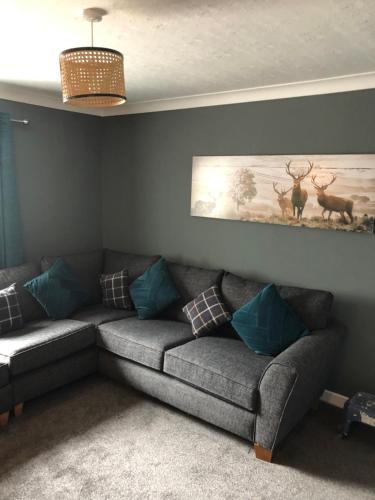 a living room with a gray couch with blue pillows at Sinclair Bay Apartments in Keiss