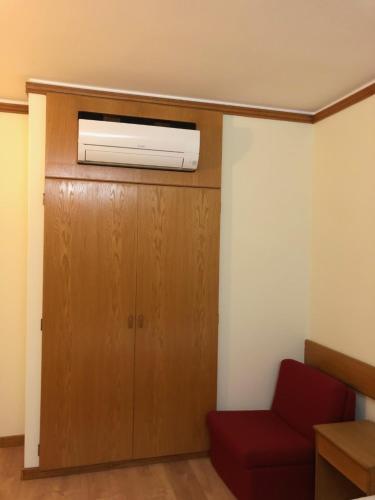 a living room with a red chair and a air conditioner at HOTEL CRUZ DA MATA in Mangualde