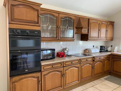 a kitchen with wooden cabinets and black appliances at Granda's House - A Home from Home near Carlingford in Carlingford