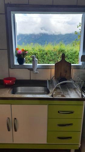 a kitchen sink with a view of a window at Casa na Montanha a 500 metros da Pedra do Baú in São Bento do Sapucaí