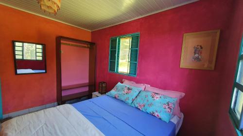 a bedroom with a bed with colorful walls and windows at Casa na Montanha a 500 metros da Pedra do Baú in São Bento do Sapucaí