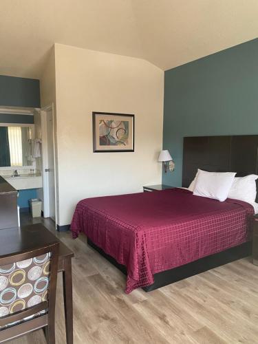 a hotel room with a bed with a red bedspread at Atascadero Inn in Atascadero