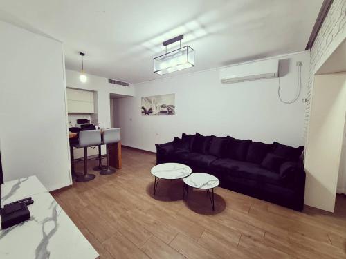 a living room with a black couch and two tables at Siesta in Achziv in Nahariyya