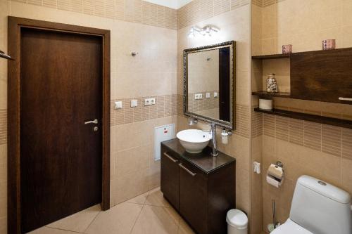 W łazience znajduje się umywalka, toaleta i lustro. w obiekcie Riga Riverside One Bedroom Apartment w Rydze