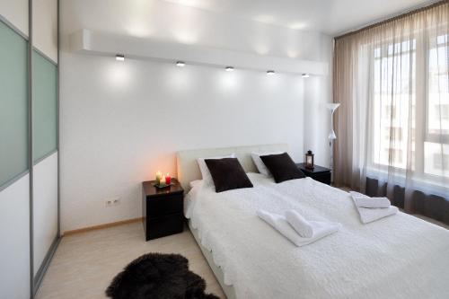 a white bedroom with a large bed with two white towels at Riga Riverside One Bedroom Apartment in Riga
