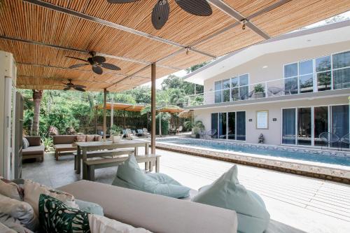 an outdoor patio with couches and a pool at Tamarindo Bay Boutique Hotel, Apartments & Suites in Tamarindo
