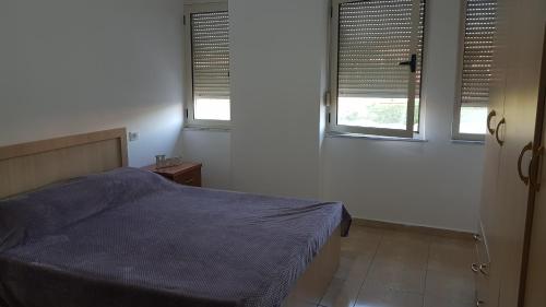 a bedroom with a blue bed and two windows at Arteg Apartments - Delux in Durrës