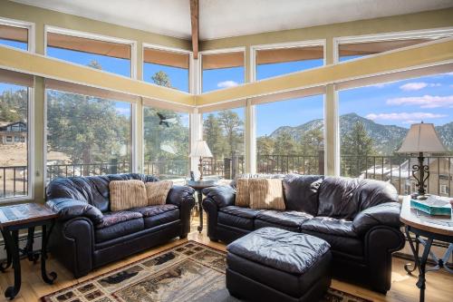 a large living room with leather couches and large windows at Starlight In The Rockies in Estes Park