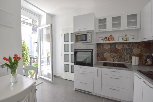 eine Küche mit weißen Schränken und einem großen Fenster in der Unterkunft Crown apartment - Your most comfortable stay in Belgrad