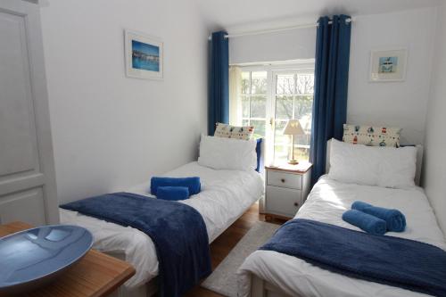 a room with two beds and a table and a window at Almond Tree Cottage in Lanteglos