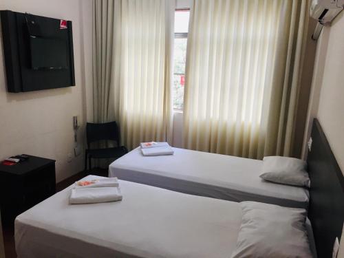 two beds in a hotel room with a television at Hotel GMatos Belo Horizonte - Próximo a Rodoviária e Mercados Turísticos in Belo Horizonte