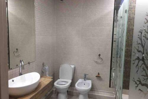 uma casa de banho com um lavatório, um WC e uma banheira em New apartment em Samarkand