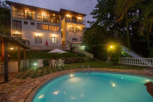 a swimming pool in front of a house at night at Hotel Pousada Arcádia Mineira in Ouro Preto