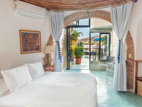 a bedroom with a white bed and a balcony at Villa Amor in Sayulita