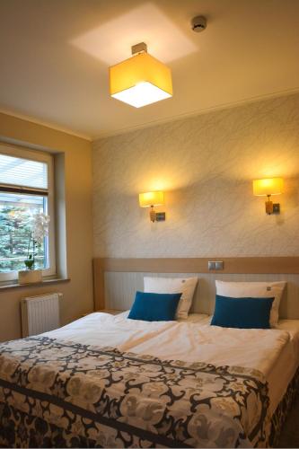 a bedroom with a large bed with blue pillows at Restauracja 32 Motel in Gryfice