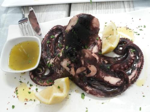 an octopus is sitting on a plate with lemon slices at B&B Brezza Marina & Ristorante Shoreline in Pozzallo