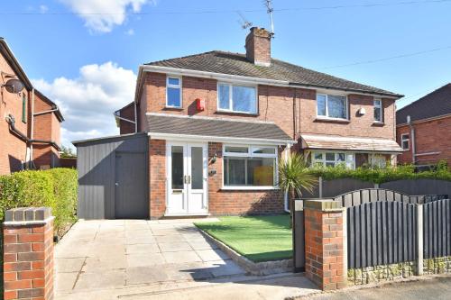a brick house with a black fence in front of it at Orion House - sleeps 6, driveway, garden in Crewe