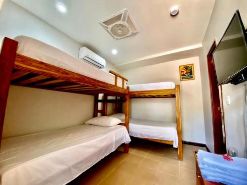 a bedroom with two bunk beds and a flat screen tv at Hostal Aurora, Smith Lodging in Taganga