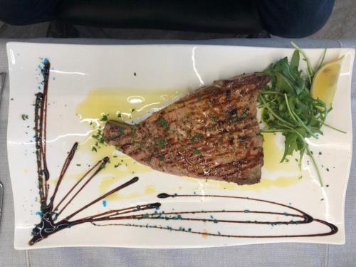 a plate of food with a piece of meat and greens at B&B Brezza Marina & Ristorante Shoreline in Pozzallo
