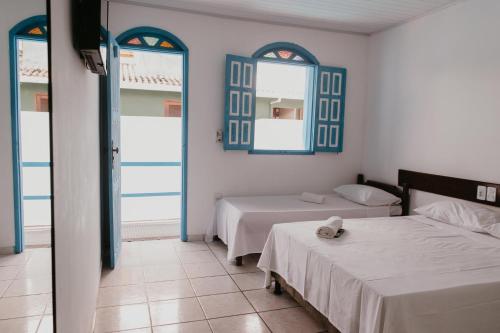 1 dormitorio con 2 camas y 2 espejos en Pousada Aluá, en Porto Seguro