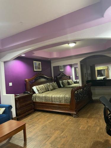 Raintree Inn and Suites في هيوستن: غرفة نوم بسرير كبير وبجدران ارجوانية