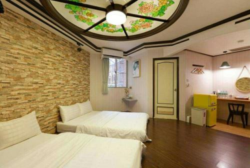 a bedroom with two beds and a brick wall at At Tainan Inn in Tainan