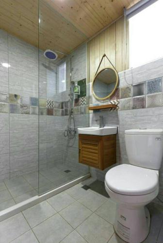 a bathroom with a toilet and a glass shower at At Tainan Inn in Tainan