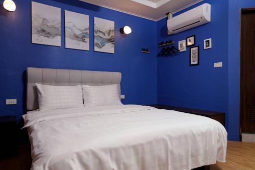 a blue bedroom with a white bed and blue walls at At Tainan Inn in Tainan