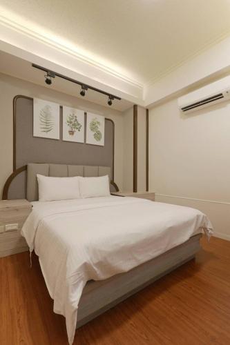 a bedroom with a large bed with white sheets at At Tainan Inn in Tainan