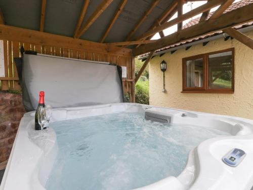 a hot tub with a bottle of wine in it at Orchard Cottage in Watchet