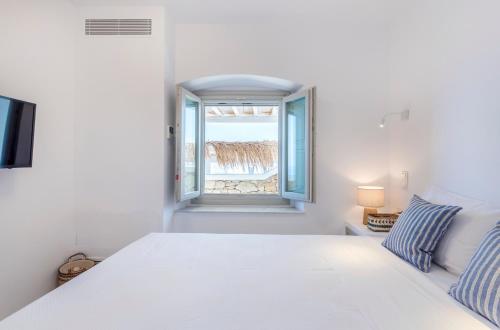 a white bedroom with a bed and a window at Bohemian Blue Villa - 7 BDRM - beach in 200m - MG Villas in Panormos Mykonos