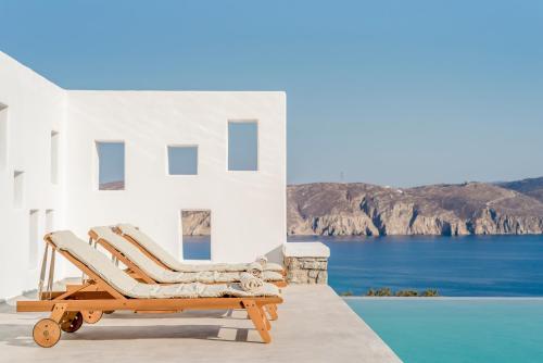 a pair of lounge chairs sitting on a patio next to a pool at Bohemian Blue Villa - 7 BDRM - beach in 200m - MG Villas in Panormos Mykonos