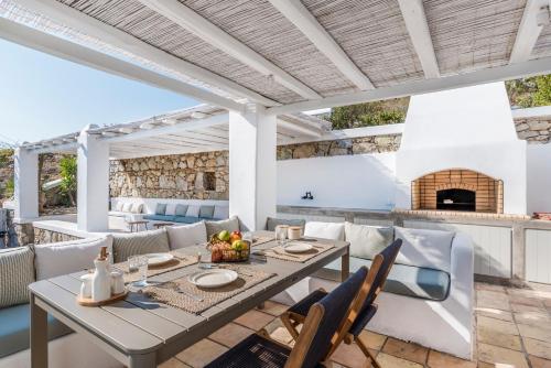 an outdoor dining room with a table and chairs and a fireplace at Bohemian Blue Villa - 7 BDRM - beach in 200m - MG Villas in Panormos Mykonos