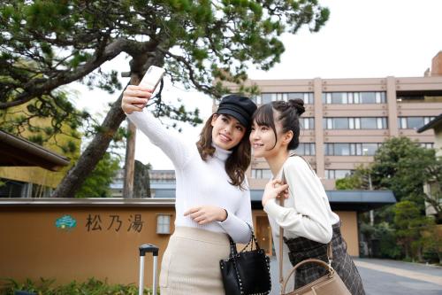 two women standing next to each other holding a cell phone at Matsunoyu in Matsue