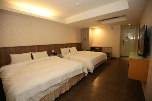a hotel room with two beds and a flat screen tv at Tai Shinu Hotel in Douliu