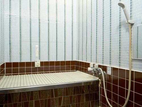 La salle de bains est pourvue d'un banc et d'une douche. dans l'établissement Takeyaso Ryokan, à Amagasaki